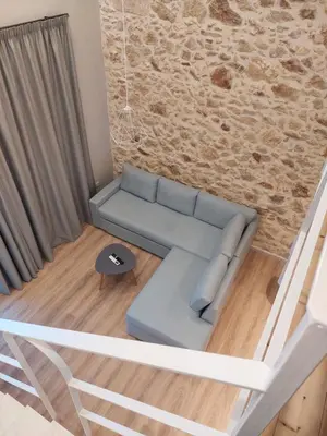 a living room with a blue couch and a stone wall at TheJoy Residence Apartments in Chania Town