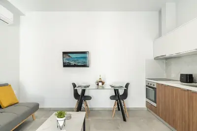 a living room with a table and a kitchen at Kiani Apts in Kalyves