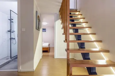 a wooden spiral staircase in a room with a bedroom at Stef&Art Old Town House in Chania Town