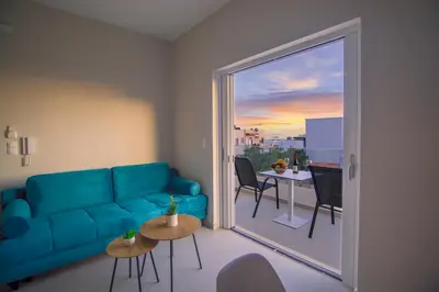 a living room with a blue couch and a sliding glass door at Vakakis Family Luxury Studios 2 in Palaiochóra