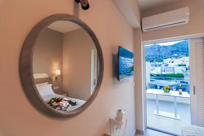 a mirror in a room with a bed and a window at Vakakis Family Luxury Studios 2 in Palaiochóra