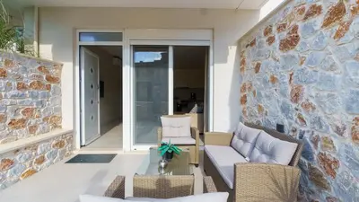 a patio with chairs and a table and a stone wall at Vakakis Family Luxury Studios 2 in Palaiochóra