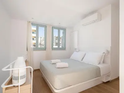 a white bedroom with a bed and two windows at Mythodea Luxury Suites in Chania Town