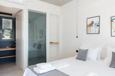 a bedroom with a white bed and a glass shower at Krystallon Villas in Palaiochóra