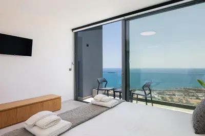 a bedroom with a bed and a large glass window at Krystallon Villas in Palaiochóra