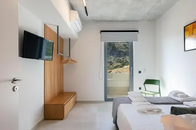 two beds in a room with a tv and a chair at Krystallon Villas in Palaiochóra