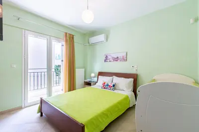 a bedroom with a green bed and a balcony at Elena Apartment in Chania Town