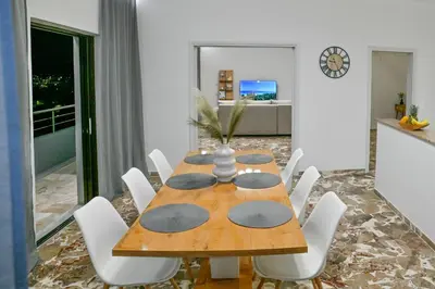 a dining room with a wooden table and white chairs at Blue Horizon Kisamos Deluxe Apartment in Kissamos