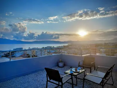 a balcony with two chairs and a table and the sunset at Blue Horizon Kisamos Deluxe Apartment in Kissamos