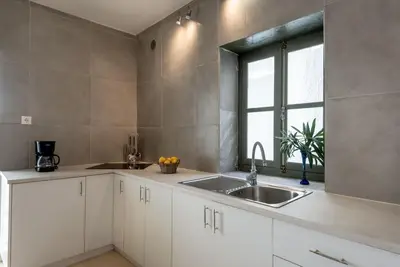 a kitchen with white cabinets and a sink and a window at Casa Lion in Chania Town