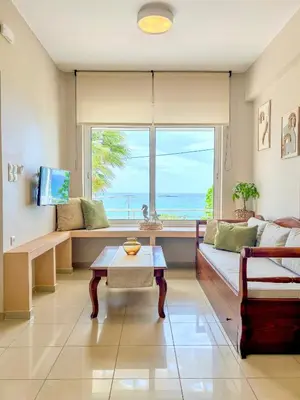 a living room with a couch and a table and a window at Vista Mare in Palaiochóra
