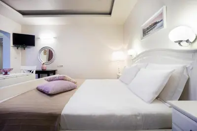 a white bedroom with a large white bed and a mirror at Casa Del Porto in Chania Town