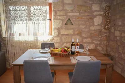 a wooden table with a basket of fruit and wine bottles at SundayMar Stone House in Chania Town