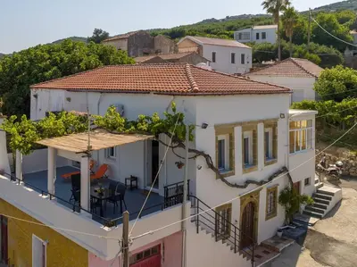 a white house with a balcony with a table at Manos Home in Spiliá