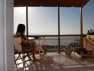 a woman sitting at a table looking out at the ocean at Nostalgia Villas in Tersanas