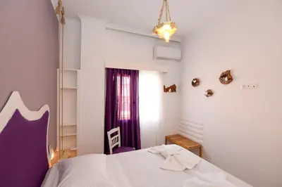 a bedroom with a white bed and a purple chair at Rubini City Apartment in Chania Town