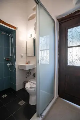 a bathroom with a toilet and a glass shower door at Marthas DeLight Rooms in Chania Town