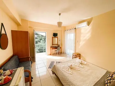 a bedroom with a bed and a couch and a table at Lefteris Rooms in Kámbos