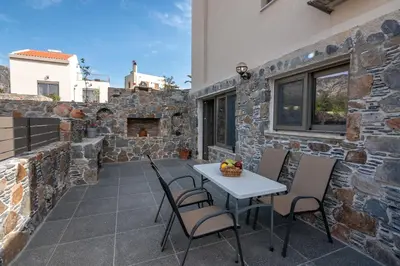 a patio with a table and chairs on a stone wall at Pink Sand-Studio in Agios Padeleimon