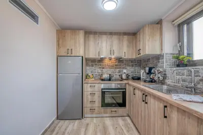 a kitchen with wooden cabinets and a stainless steel refrigerator at Pink Sand-Studio in Agios Padeleimon