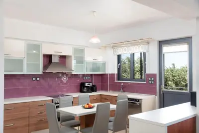 a kitchen with a table and chairs and purple walls at Villa Gianta in Kissamos