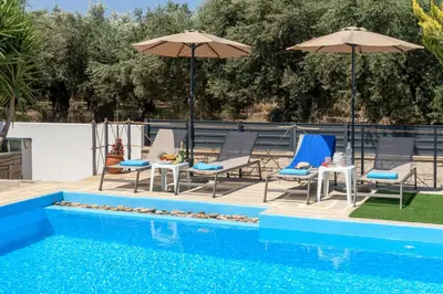 a group of chairs and umbrellas next to a pool at Villa Gianta in Kissamos