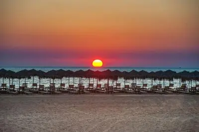 a sunset over the beach with a group of umbrellas at CASA di LIMONI in Kissamos