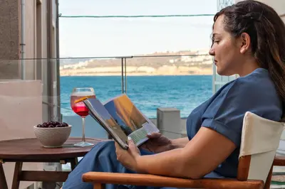 a woman sitting in a chair reading a book at La 'belle Luxury House Chania in Chania Town