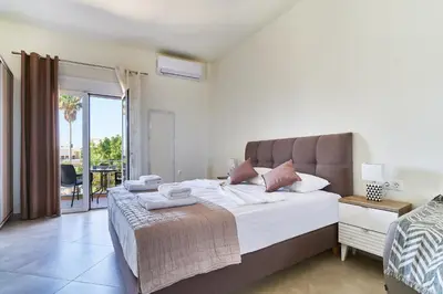 a bedroom with a large bed and a balcony at Bella Apartment in Kissamos