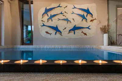 a swimming pool with candles in front of a painting of dolphins at Caneva Luxury Villa in Tavronitis