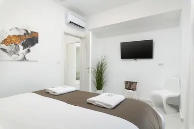 a white bedroom with a bed and a flat screen tv at Tholaria Villa in Chania Town