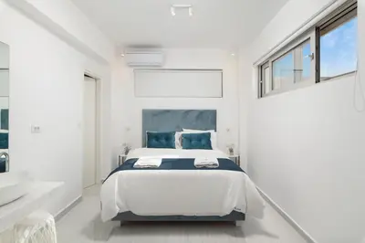 a white bedroom with a bed and a sink at Tholaria Villa in Chania Town
