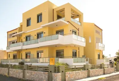 a yellow building with a fence in front of it at Evriali Comfort Living in Palaiochóra