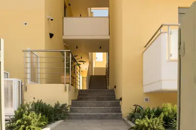 a staircase leading up to a house with yellow walls at Evriali Comfort Living in Palaiochóra