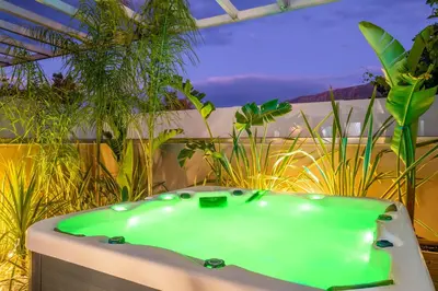 a green bath tub in a room with plants at Delight Luxury Residences - Souda in Souda