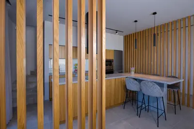 a kitchen with wooden walls and a counter with stools at Xenias Luxury Villas Kalathas in Kalathas