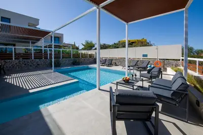 a swimming pool with a group of chairs next to it at Xenias Luxury Villas Kalathas in Kalathas