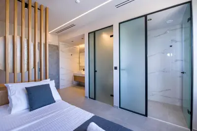 a bedroom with a large white bed and glass walls at Xenias Luxury Villas Kalathas in Kalathas