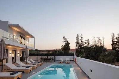 a house with a swimming pool and lounge chairs at Horizon Luxury Villa in Chania Town
