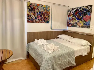 a bedroom with a bed with a table and a painting at RITSA ART RESIDENCE in Chania Town