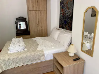 a bedroom with a bed with white sheets and a mirror at RITSA ART RESIDENCE in Chania Town