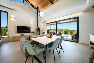 a dining room with a table and chairs and a television at Villa Olira in Alikianós
