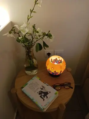 a table with a book and a vase of flowers and a candle at casa di nonna in Chania Town