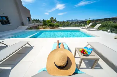 a person laying on a chair next to a swimming pool at Villa Florentina at Chania Suburbs With Private Pool and BBQ in Alikianós