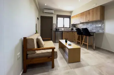 a living room with a couch and a table and a kitchen at Thea Studio in Agios Padeleimon