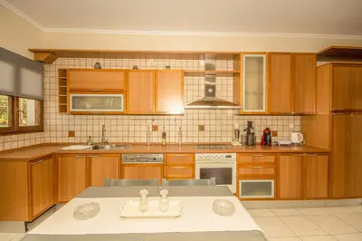 a large kitchen with wooden cabinets and a sink at Strevagio family house in Kissamos