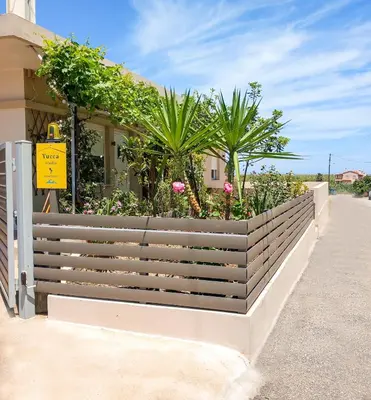 a wooden fence with flowers and plants on it at Yucca Studio, beautiful apartment with garden in Ropanianá