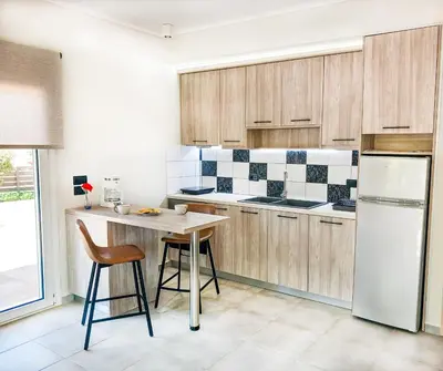 a kitchen with wooden cabinets and a table and a refrigerator at Yucca Studio, beautiful apartment with garden in Ropanianá