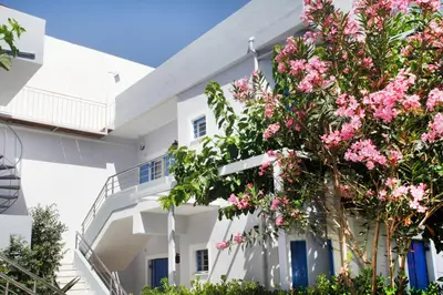 a white building with pink flowers in front of it at Studios Vasilis in Agia Marina Nea Kydonias
