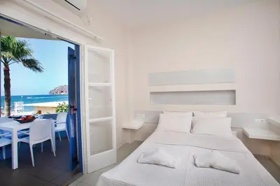 a bedroom with a bed and a table with a view of the ocean at Studios Vasilis in Agia Marina Nea Kydonias